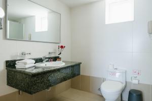 a bathroom with a sink and a toilet and a mirror at Theo Sunset Bay Hotel in Paphos