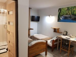 a room with two beds and a desk and a bathroom at Hotel "ZAUŁEK" Spółka Cywilna Zbigniew Świderski, Elżbieta Świderska in Olszyna