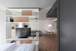 a bedroom with a bed and a desk with a tv at SMARTments business München Parkstadt Schwabing in Munich
