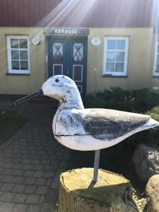 a bird statue sitting on a stump in front of a house at "Steuermannskammer" by Ferienhaus Strandgut in Born +11 photos