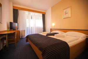 a hotel room with two beds and a desk at Hotel Dražica - Hotel Resort Dražica in Krk