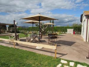 a patio with tables and chairs and an umbrella at Agriturismo Sweet Cottage in Marina di Grosseto