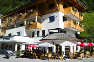 ein Hotel mit Tischen und Sonnenschirmen davor in der Unterkunft Hotel Tannenhof in Ischgl