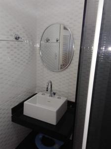W białej łazience znajduje się umywalka i lustro. w obiekcie Casa com piscina e churrasqueira w mieście Iguaba Grande