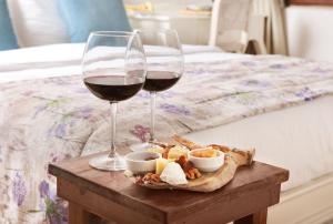 dos copas de vino y aperitivos en una mesa junto a una cama en VINIFERA VINEYARDS HOTEL, en Selçuk