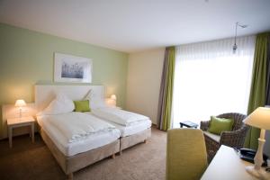 a bedroom with a large white bed and a living room at Paulsen's Landhotel und Restaurant in Bohmstedt