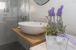 a bathroom with a sink and a vase with purple flowers at Seafront apartment in historical Cippico castle in Kaštela