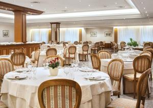 una sala da pranzo con tavoli e sedie bianchi di Hotel Fiuggi Terme Resort & Spa a Fiuggi