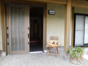 a surfboard sitting on a chair in front of a house at Nouka Minsyuku Hyousa in Minamiechizen