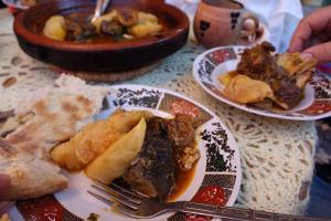 a table with plates of food and a bowl of food at Ijoukak Berber HomeStay in Ijjoukak