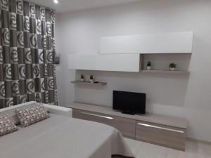 a white living room with a tv and a couch at La casa di Donatella in Naples