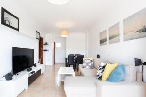 a white living room with a white couch and a tv at Home2Book Beautiful Duplex Arona in Arona