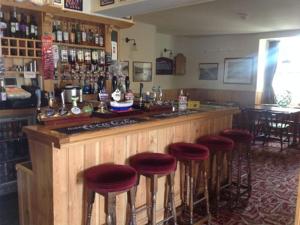 a bar with red stools in a room with a counter at The Safe Harbour Hotel in Fowey