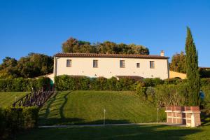 ein großes weißes Haus auf einem grünen Hügel in der Unterkunft Casa Vacanze "Casale al Pino" in Riparbella