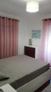 ナザレにあるApartamento Nazaréのベッドルーム1室(ピンクのカーテン付きのベッド1台付)