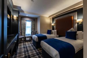 um quarto de hotel com duas camas e uma televisão em Fir Trees Hotel em Strabane