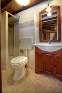 uma casa de banho com um WC, um lavatório e um espelho. em Al Castello em Brolo