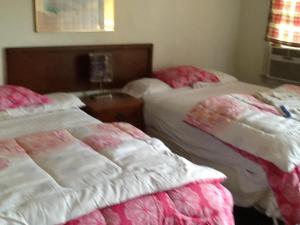 two beds sitting next to each other in a bedroom at Rosenberg Motel in Galveston