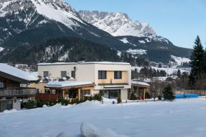 dom w śniegu z górami w tle w obiekcie Appartement Hoschek w mieście Scheffau am Wilden Kaiser