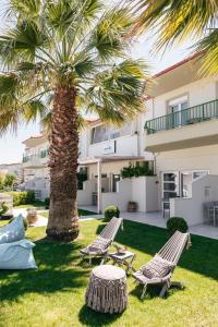 una palmera y dos sillas y una mesa frente a una casa en Minthi Boutique Apartments, en Chaniotis