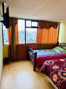 1 dormitorio con 2 camas y ventana grande en Hostal Rosita Latacunga en Latacunga