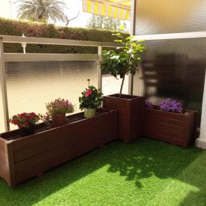 eine Terrasse mit drei Topfpflanzen und Gras in der Unterkunft APARTAMENTO EN LA PLAYA in Miami Platja