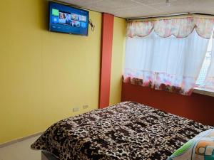 a bedroom with a bed and a tv on the wall at Hostal Rosita Latacunga in Latacunga