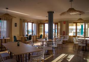 a restaurant with wooden tables and chairs and windows at Bellavista Bolonia in Bolonia