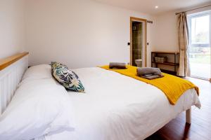 a bedroom with a large white bed with yellow sheets at Maple – Three Tuns Apartments in Pettistree