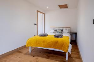 een slaapkamer met een bed met een gele deken bij Maple – Three Tuns Apartments in Pettistree