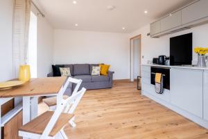 een keuken en een woonkamer met een tafel en een bank bij Maple – Three Tuns Apartments in Pettistree