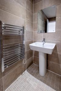 a bathroom with a sink and a mirror and a shower at Maple – Three Tuns Apartments in Pettistree