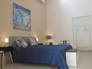 Un dormitorio con una cama azul y una pintura en la pared en Polpo e Polpessa Casa Vacanze, en Lipari
