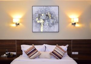 a bedroom with a bed with two lamps and a painting at Razana Hotel in Nairobi +30 photos