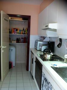 une cuisine avec des murs roses et des armoires blanches dans l'établissement Spacieux Appartement au coin de la plage, à Middelkerke