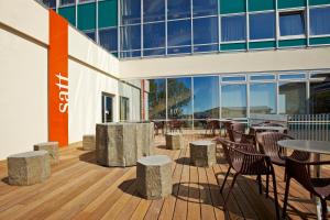 a deck with tables and chairs and a building at Reykjavik Natura - Berjaya Iceland Hotels in Reykjav&iacute;k