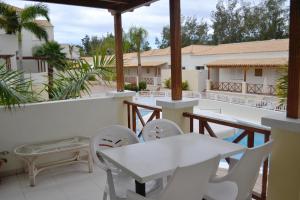 un patio con mesas blancas y sillas en el balcón en Golf Resort Tenerife sur, en Los Cristianos