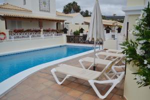 ロス・クリスティアーノスにあるGolf Resort Tenerife surのラウンジチェア2脚とパラソル付きのプールが備わります。