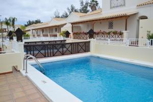 a swimming pool in front of a house at Golf Resort Tenerife sur in Los Cristianos
