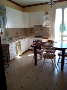 een keuken met witte kasten en een tafel en stoelen bij CASA DEGLI OLEANDRI in Carlentini