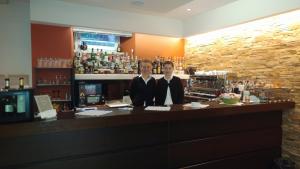 dos personas de pie en un bar en un bar en Hotel Posta, en Moltrasio