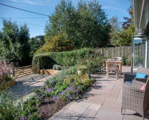 - un jardin avec une terrasse agrémentée de chaises et de fleurs dans l'établissement Hill Stables, à Woodbridge