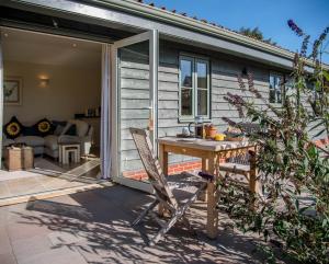 a sliding glass door opens onto a patio with a table at Hill Stables in Woodbridge