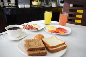 a table with two plates of breakfast foods and a cup of coffee at Delfines Apart Hotel in La Paz