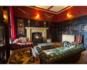 een woonkamer met lederen meubels en een open haard bij Augill Castle in Kirkby Stephen