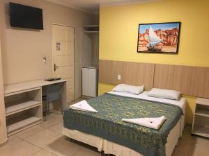 a room with a bed and a desk and a computer at Hotel Pousada Latitude in Canoa Quebrada +159 photos