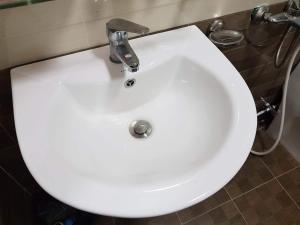 Un lavabo blanco con grifo en un baño. en Duy Hotel, en Da Lat