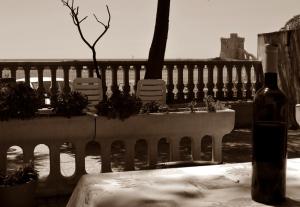 a bottle of wine sitting on a table next to a fence at Bed And Breakfast Li Scianuli in Porto Cesareo