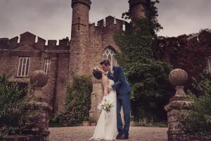 een bruid en bruidegom die voor een kasteel staan bij Augill Castle in Kirkby Stephen