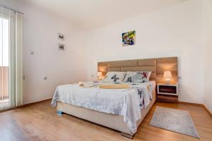 a white bedroom with a large bed and a window at Libra Apartments in Tivat